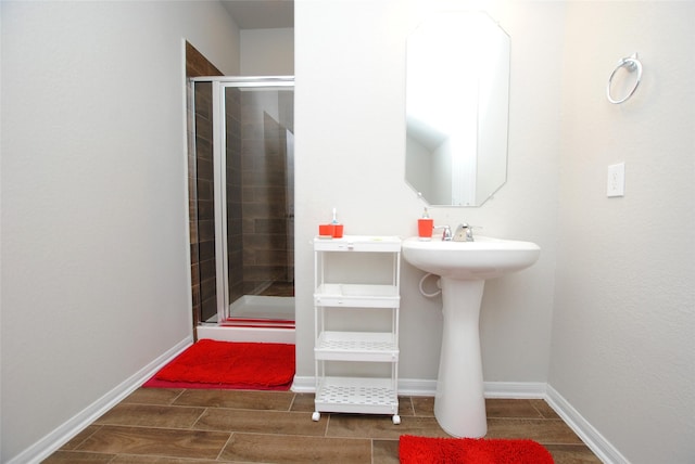 bathroom featuring a shower with door and sink