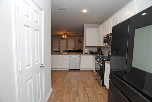 kitchen featuring stainless steel appliances, backsplash, white cabinets, and light hardwood / wood-style floors