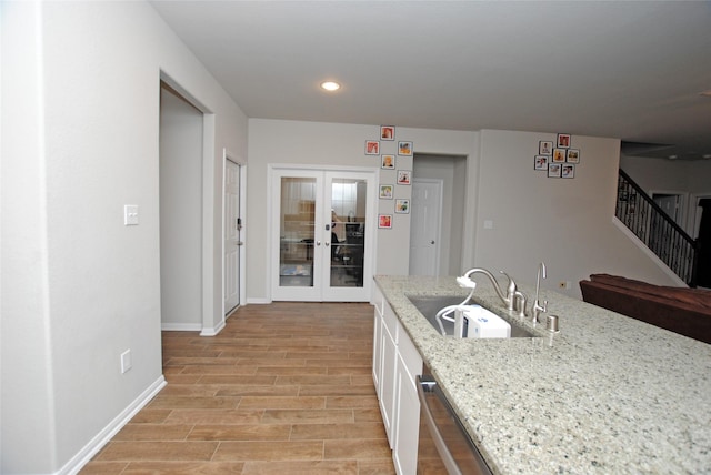 kitchen with sink, dishwasher, white cabinetry, light stone countertops, and french doors