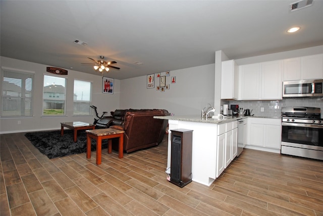 kitchen featuring white cabinetry, light stone countertops, kitchen peninsula, and appliances with stainless steel finishes