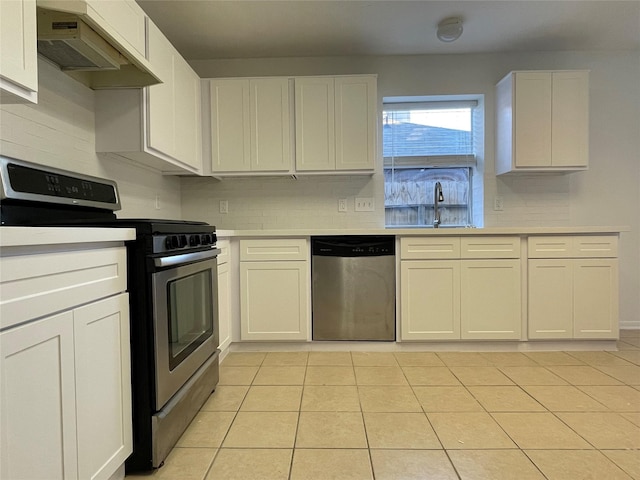 kitchen with appliances with stainless steel finishes, tasteful backsplash, white cabinetry, sink, and light tile patterned floors