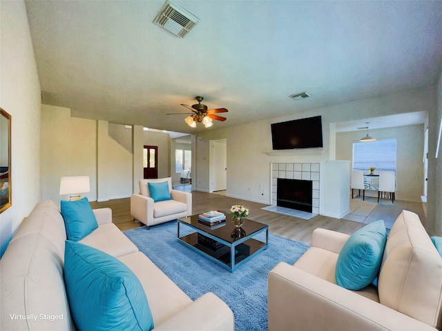 living room with a fireplace, light hardwood / wood-style floors, and ceiling fan