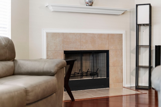 details with hardwood / wood-style flooring and a tiled fireplace