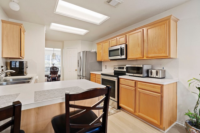 kitchen featuring sink, a breakfast bar area, stainless steel appliances, and light wood-type flooring