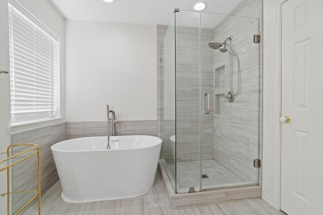 bathroom with tile walls and shower with separate bathtub