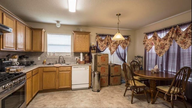 kitchen with hanging light fixtures, gas range, sink, and white dishwasher