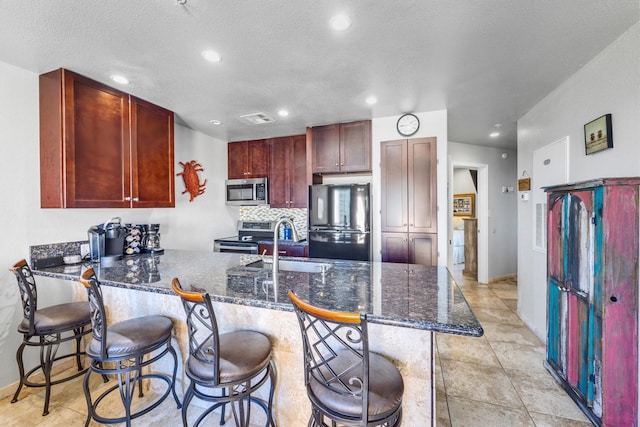 9520 Seawall Blvd Unit 354, Galveston, TX 77554 - kitchen featuring appliances with stainless steel finishes, reddish brown cabinets, a sink, a peninsula, and recessed lighting
