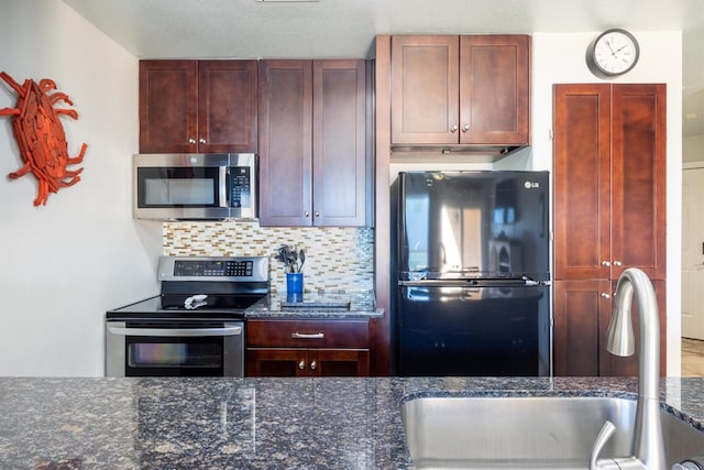 9520 Seawall Blvd Unit 354, Galveston, TX 77554 - kitchen with stainless steel appliances, a sink, decorative backsplash, dark stone counters, and reddish brown cabinets