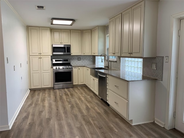 kitchen with tasteful backsplash, appliances with stainless steel finishes, sink, and stone counters