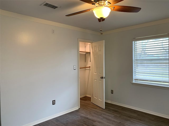 unfurnished bedroom with ceiling fan, dark hardwood / wood-style floors, and a spacious closet