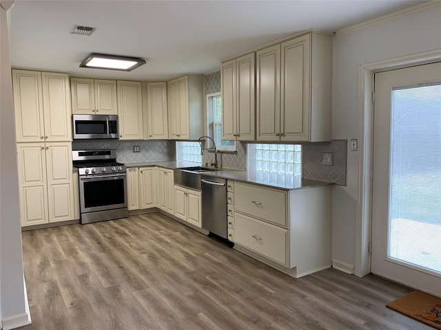 kitchen with cream cabinets, stainless steel appliances, sink, and backsplash