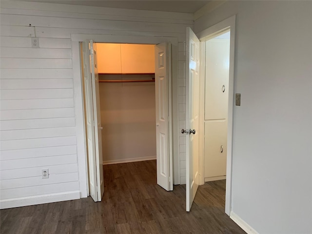 interior space with dark hardwood / wood-style flooring and wood walls