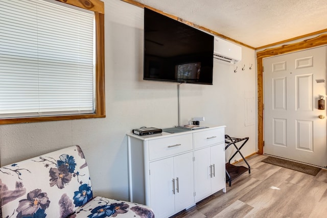 bedroom featuring a wall mounted air conditioner, a textured ceiling, and light wood-type flooring