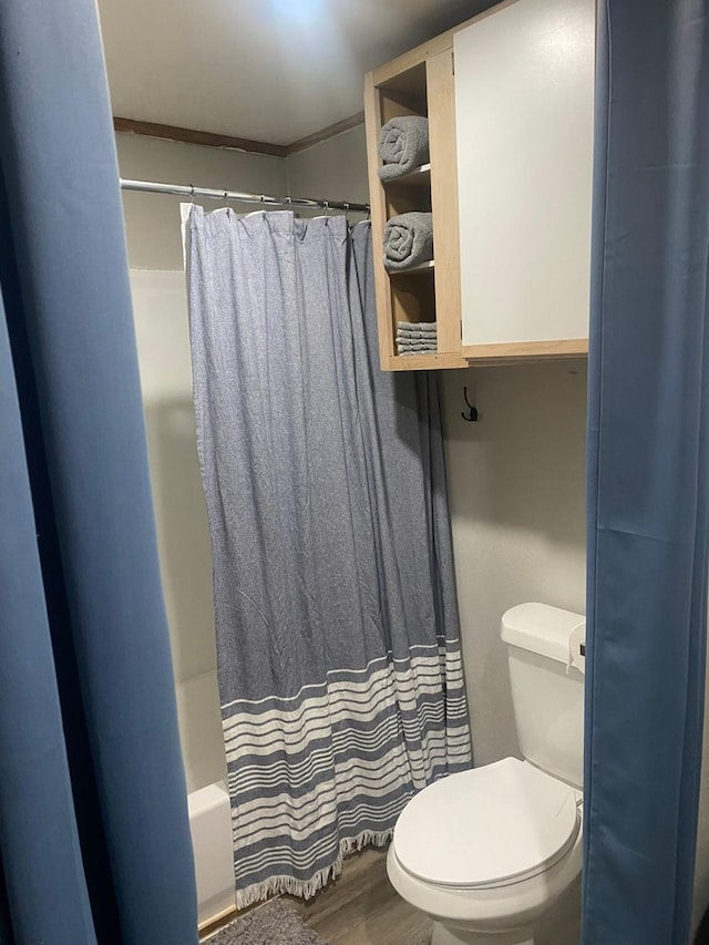 bathroom with hardwood / wood-style flooring, shower / tub combo with curtain, ornamental molding, and toilet