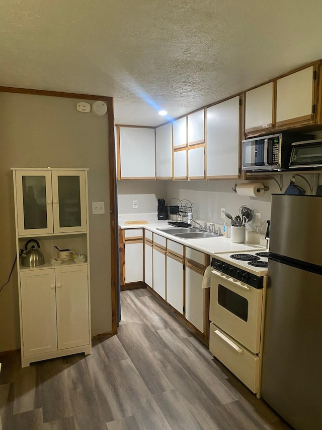 kitchen featuring sink, a textured ceiling, stainless steel appliances, light hardwood / wood-style floors, and white cabinets