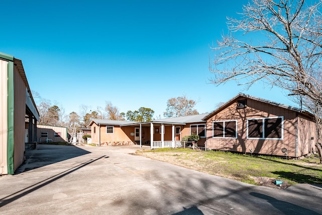 rear view of property featuring a yard and covered porch