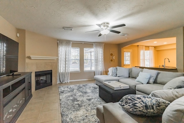 living room featuring light tile patterned flooring, plenty of natural light, a fireplace, and a textured ceiling