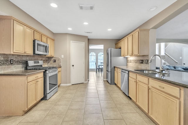 kitchen with sink, light tile patterned floors, appliances with stainless steel finishes, backsplash, and light brown cabinets