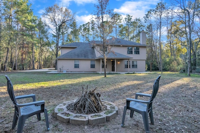 rear view of property with a lawn and an outdoor fire pit