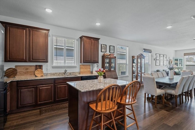 kitchen featuring dark hardwood / wood-style flooring, sink, a kitchen bar, and a kitchen island