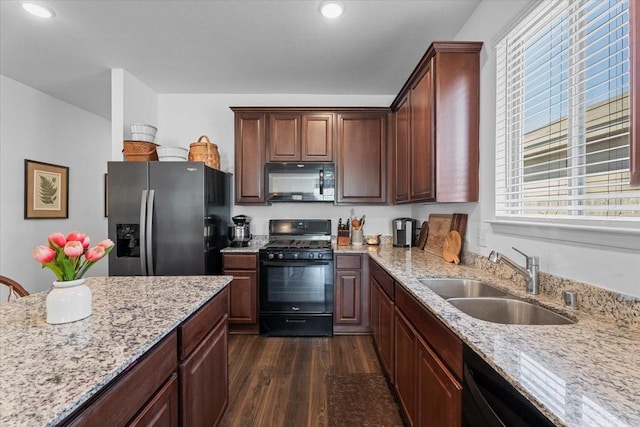 kitchen featuring dark hardwood / wood-style flooring, light stone countertops, sink, and black appliances