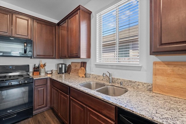 kitchen featuring black appliances, sink, light stone counters, dark brown cabinetry, and dark wood-type flooring