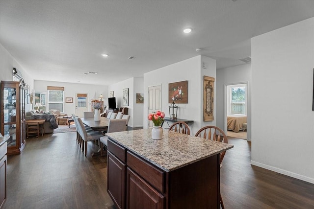 kitchen with dark brown cabinets, a center island, a wealth of natural light, and dark hardwood / wood-style flooring