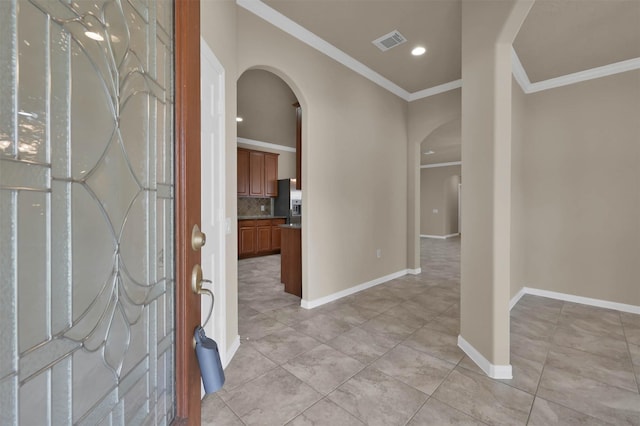 foyer entrance with ornamental molding and light tile patterned floors