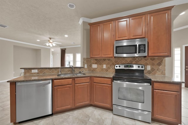 kitchen with sink, crown molding, appliances with stainless steel finishes, stone countertops, and kitchen peninsula