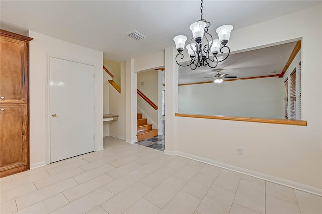 spare room featuring ceiling fan with notable chandelier