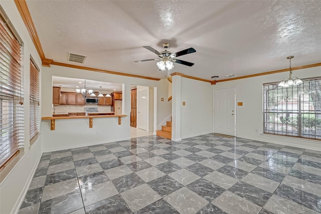 unfurnished living room with ornamental molding, ceiling fan with notable chandelier, and a textured ceiling