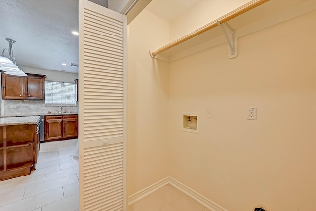 clothes washing area featuring washer hookup, sink, and light tile patterned floors