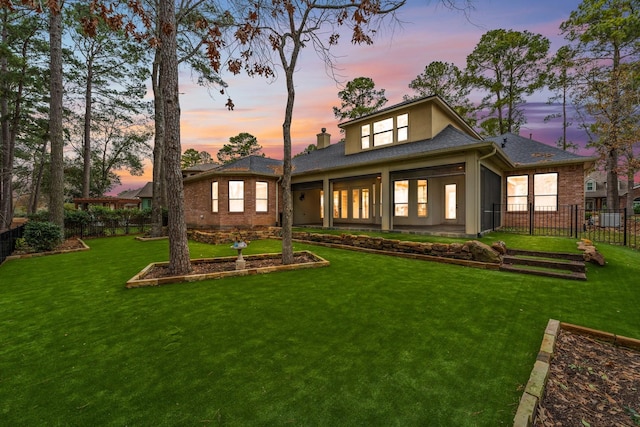 back house at dusk with a lawn