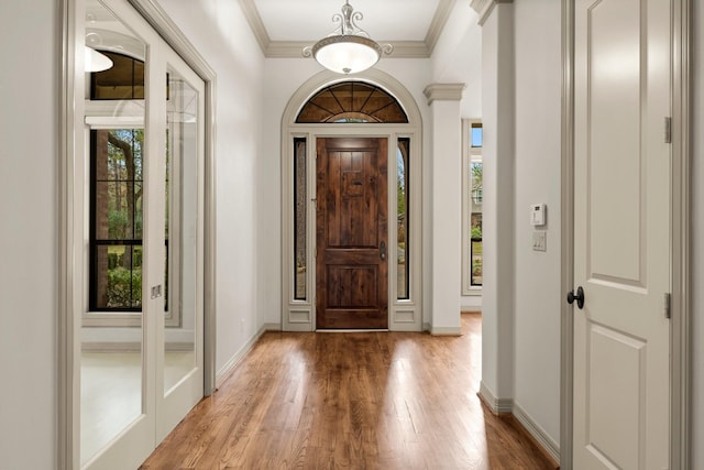 entryway featuring crown molding, a wealth of natural light, and wood-type flooring