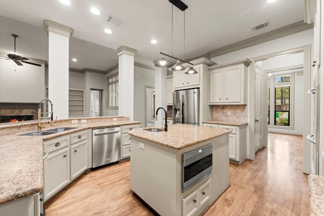 kitchen with stainless steel appliances, light stone countertops, sink, and hanging light fixtures