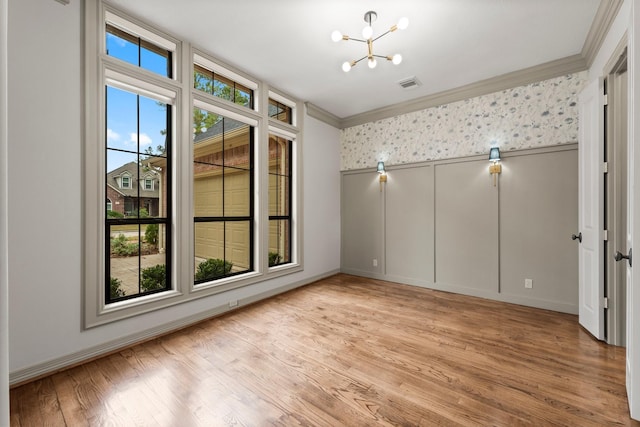 unfurnished room with crown molding, a notable chandelier, and light hardwood / wood-style flooring