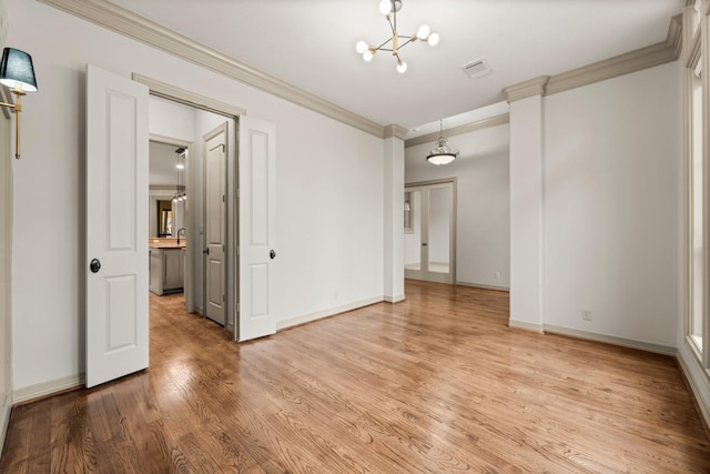 spare room featuring an inviting chandelier, hardwood / wood-style floors, and crown molding