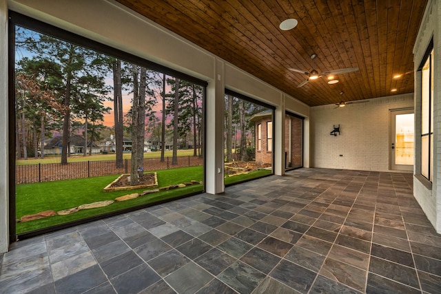 unfurnished sunroom with ceiling fan and wooden ceiling