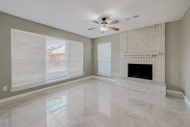 unfurnished living room with ceiling fan, light tile patterned floors, a fireplace, and a textured ceiling