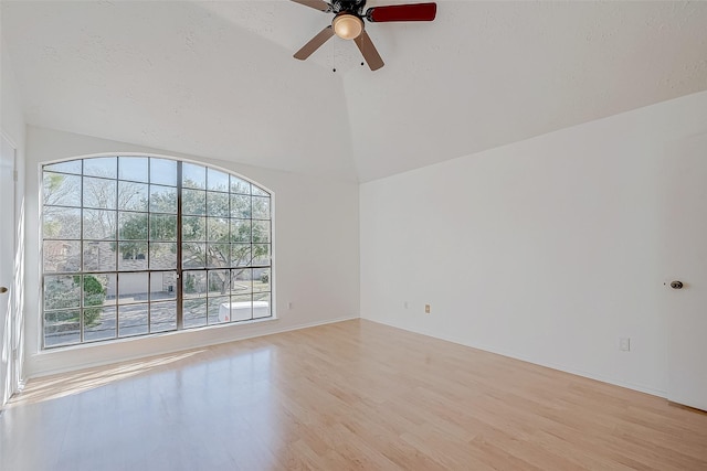 spare room featuring vaulted ceiling, a healthy amount of sunlight, ceiling fan, and light wood-type flooring