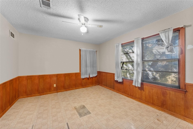 empty room with ceiling fan and a textured ceiling