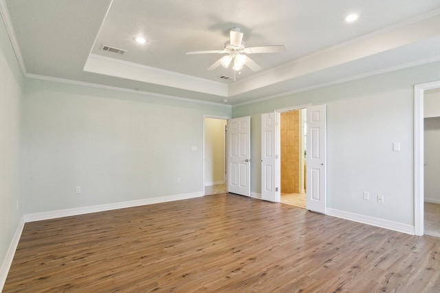 unfurnished bedroom featuring ornamental molding, wood-type flooring, ceiling fan, and a tray ceiling