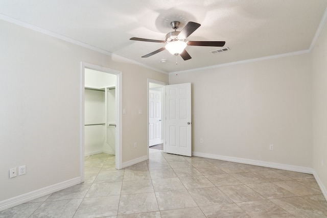 unfurnished bedroom featuring crown molding, ceiling fan, a closet, and a walk in closet