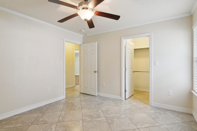 unfurnished bedroom featuring ornamental molding, a walk in closet, light tile patterned floors, ceiling fan, and a closet