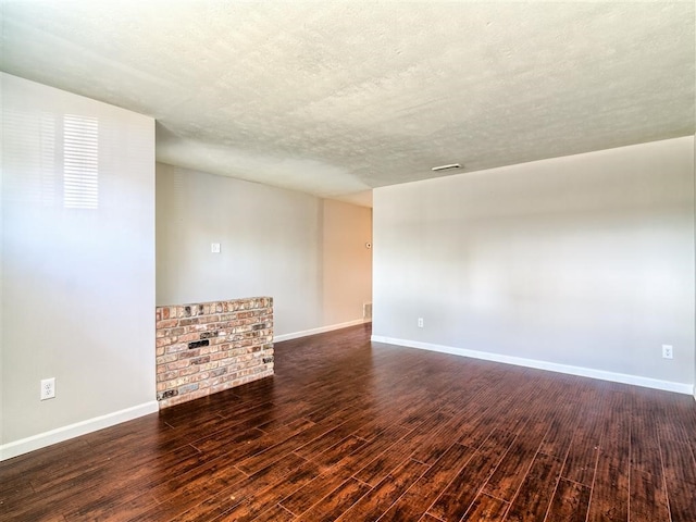 spare room featuring dark hardwood / wood-style flooring and a textured ceiling