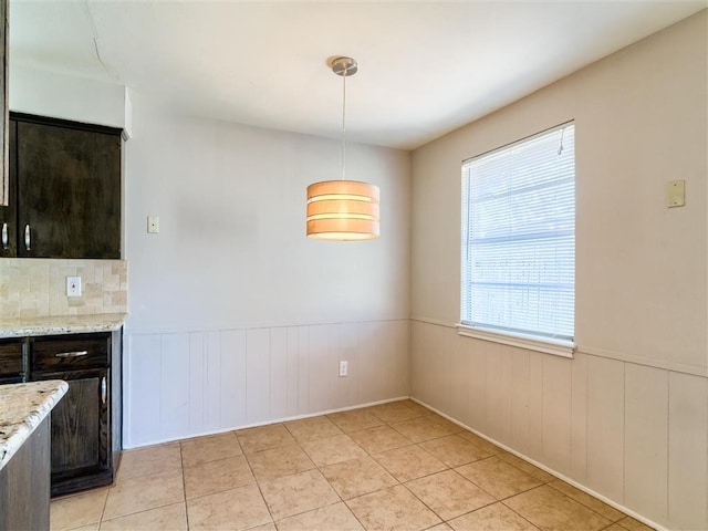 kitchen featuring light stone countertops, light tile patterned floors, dark brown cabinetry, and decorative light fixtures