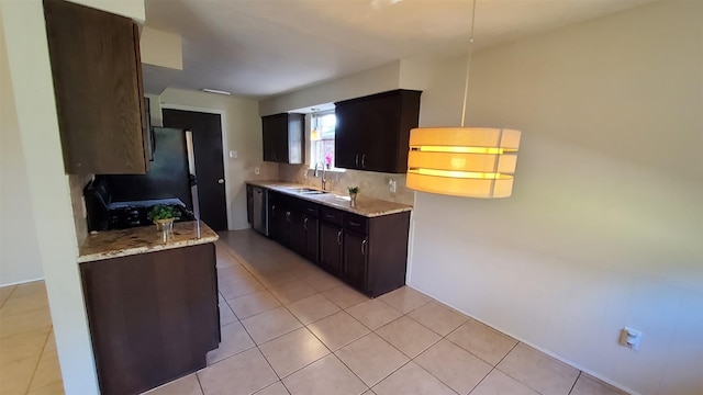 kitchen with dark brown cabinetry, sink, tasteful backsplash, light stone counters, and light tile patterned floors