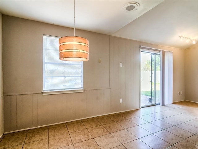 tiled empty room featuring vaulted ceiling