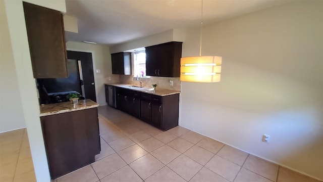 kitchen featuring dark brown cabinetry, sink, light stone counters, light tile patterned floors, and backsplash