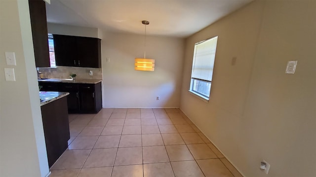 kitchen featuring light stone counters, decorative light fixtures, decorative backsplash, and light tile patterned floors